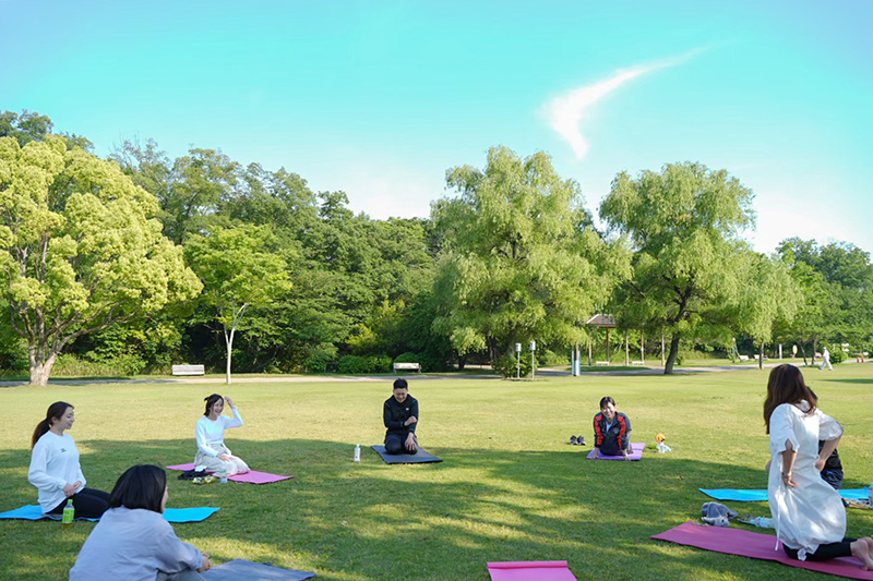 青空と芝生が広がる公園でヨガ