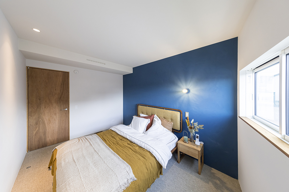 鮮やかなブルーのアクセントウォールがかっこいいダブルベッドのある寝室 黒が美しいワンランク上の平屋施工事例