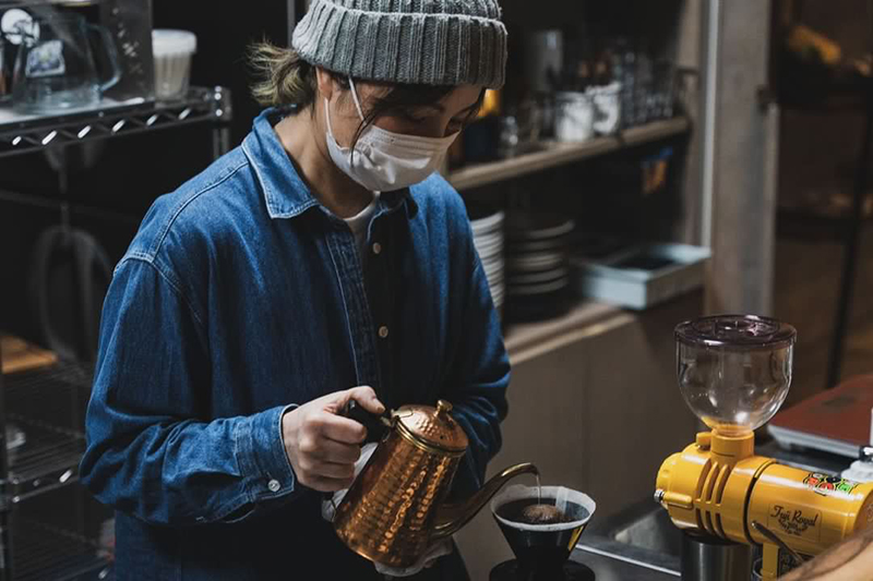 ニット帽をかぶったコーヒーを淹れる女性