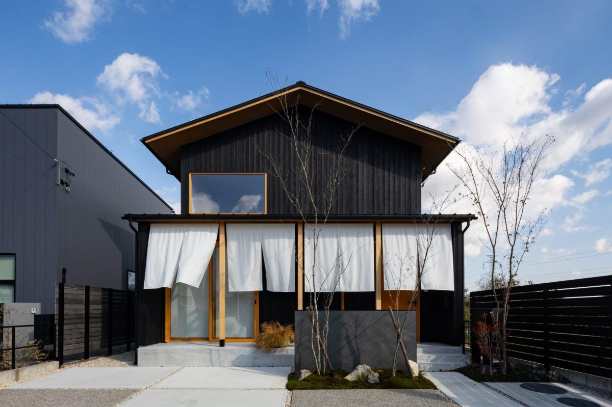 焼杉の外壁と風になびく暖簾が美しい日本建築の外観